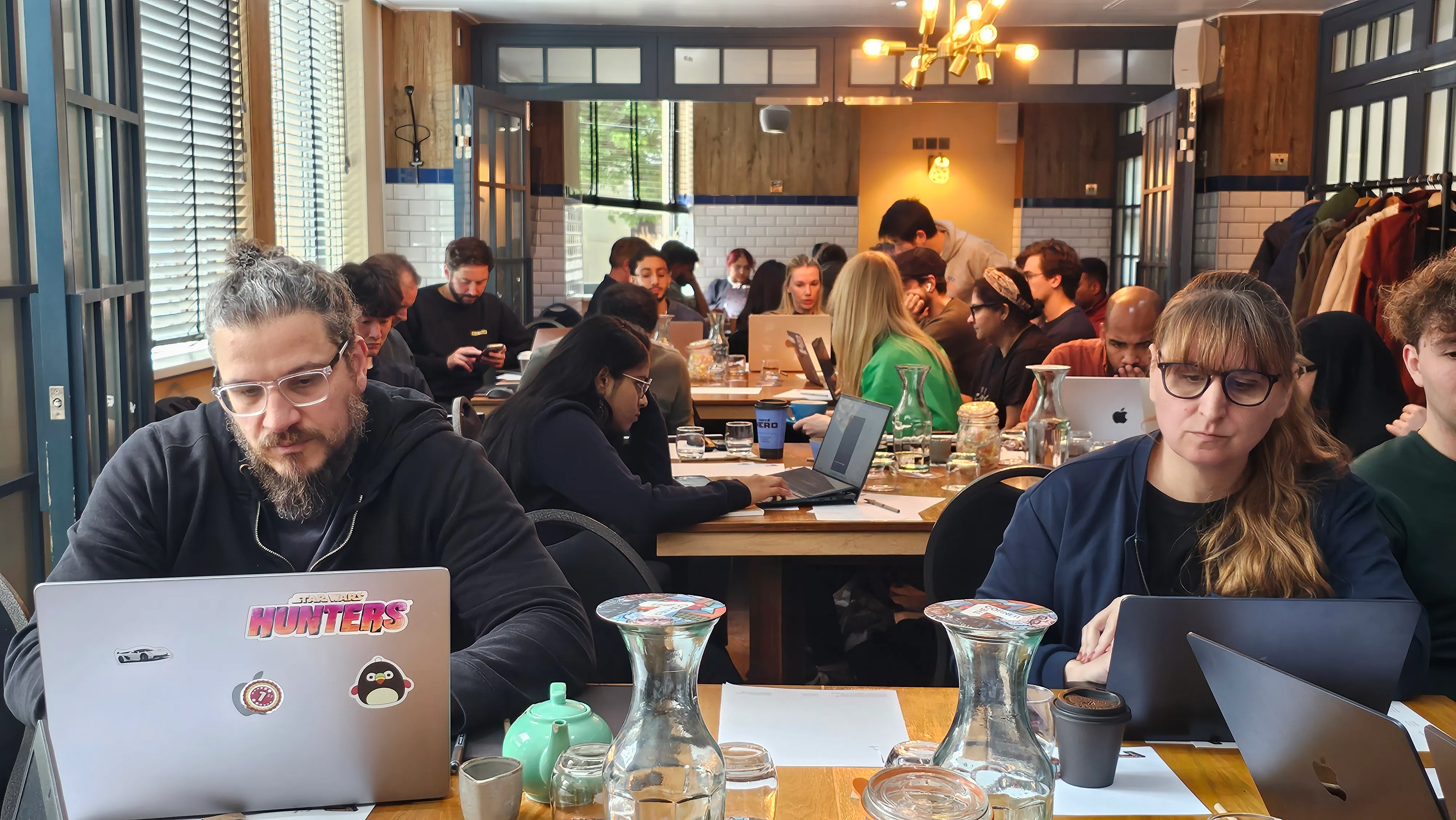Professionals working on laptops around shared tables at an Atlas Learn AI workshop in London