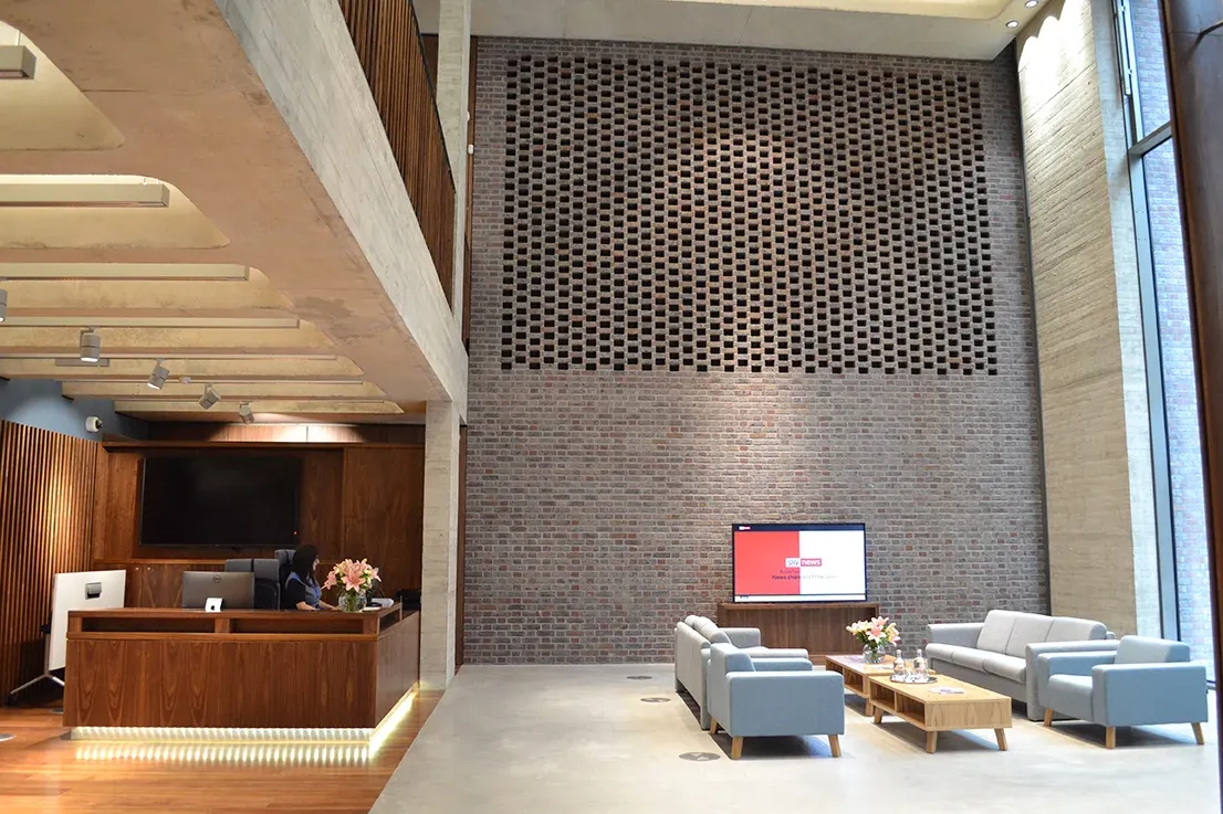 The double-height entrance at No6, reception desk to the left of a full-height brick wall.